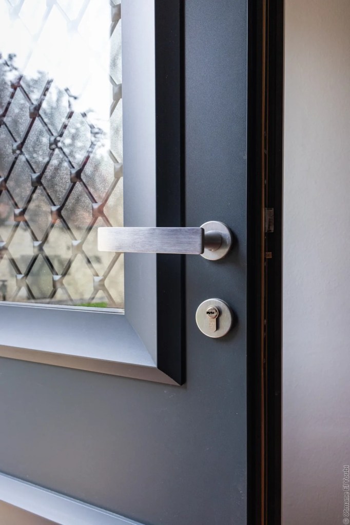 Poignée et vitrage décoratif d’une porte d’entrée grise du réseau OuvertureS