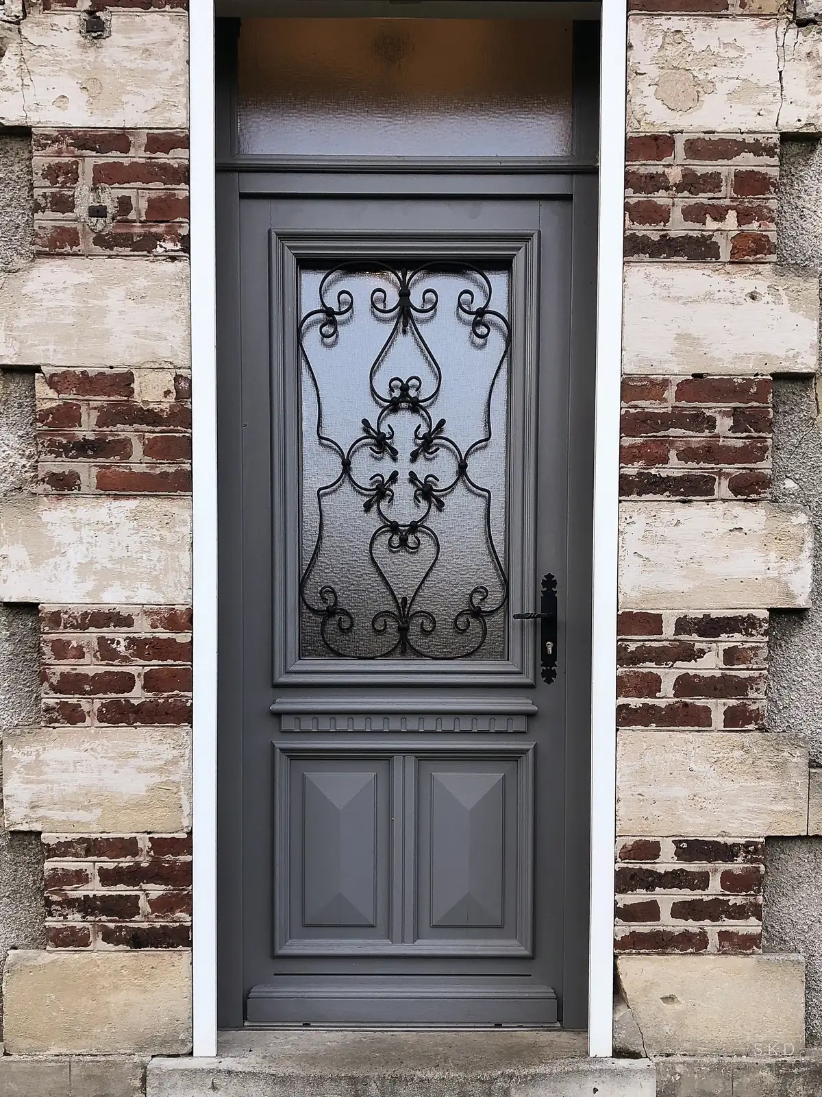 Porte d’entrée grise avec ferronnerie, façade en brique et pierre à Reims